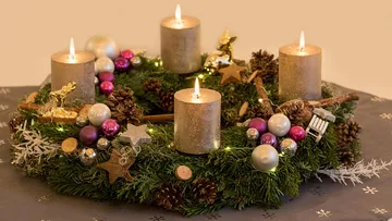 Adventskranz mit Kerzen auf Tisch.