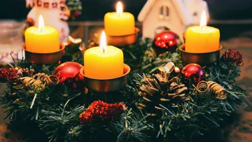 Four glowing candles on a festive wreath.