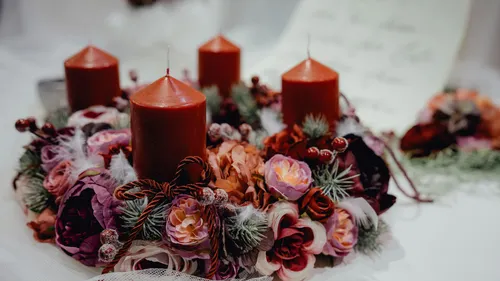 Red candles on floral wreath, festive table.