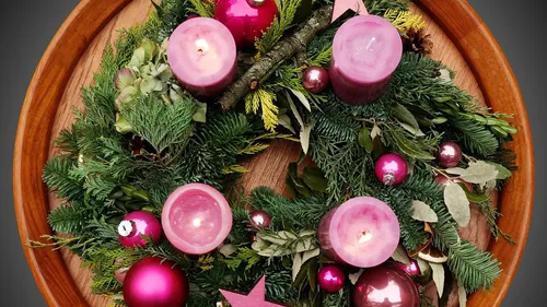 Kranz mit pinken Kerzen auf Holztablett.