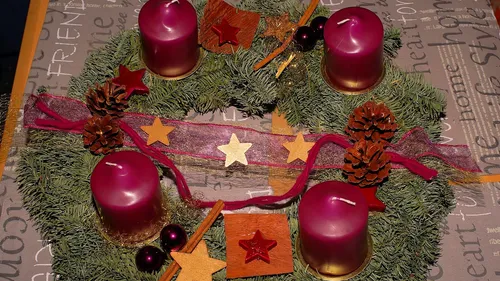 Advent wreath with four red candles and pine cones.