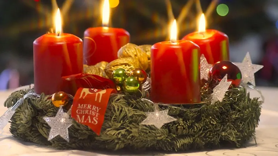 Red candles on decorative Christmas wreath.
