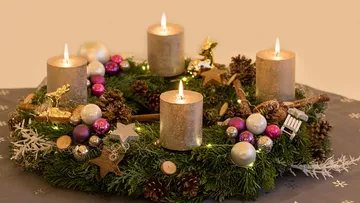Candles on decorated Christmas wreath with ornaments.