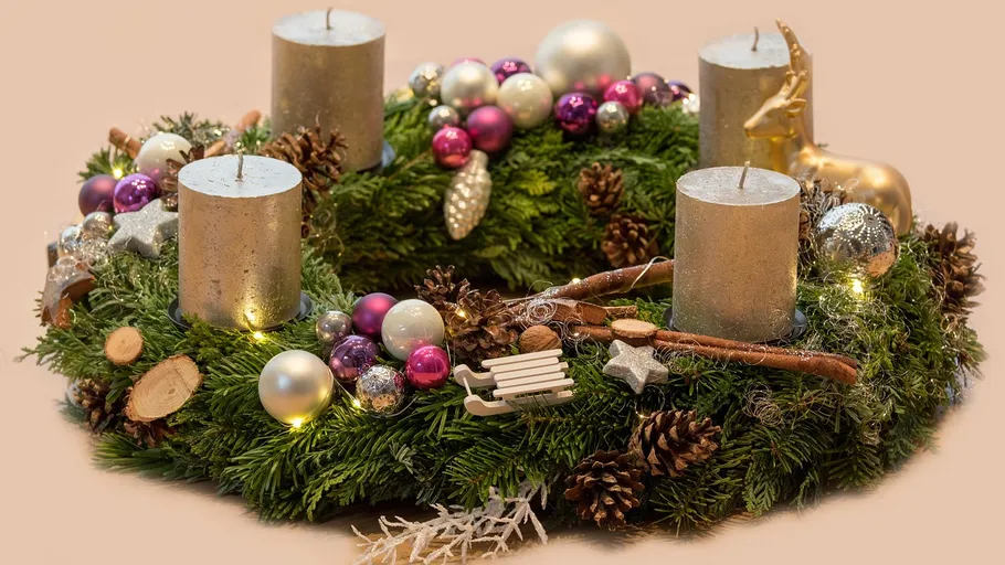 Festlicher Kranz mit Kerzen und Ornamenten.
