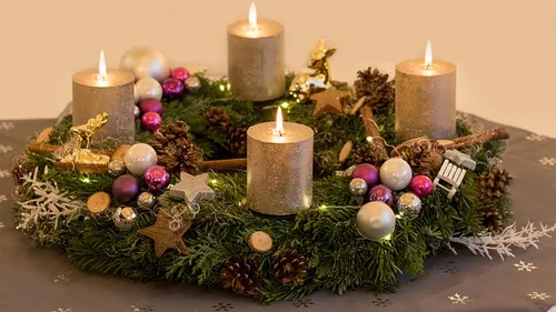 Adventskranz mit vier brennenden Kerzen, festliche Dekorationen.
