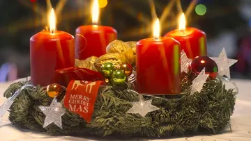 Four lit red candles on a Christmas wreath.