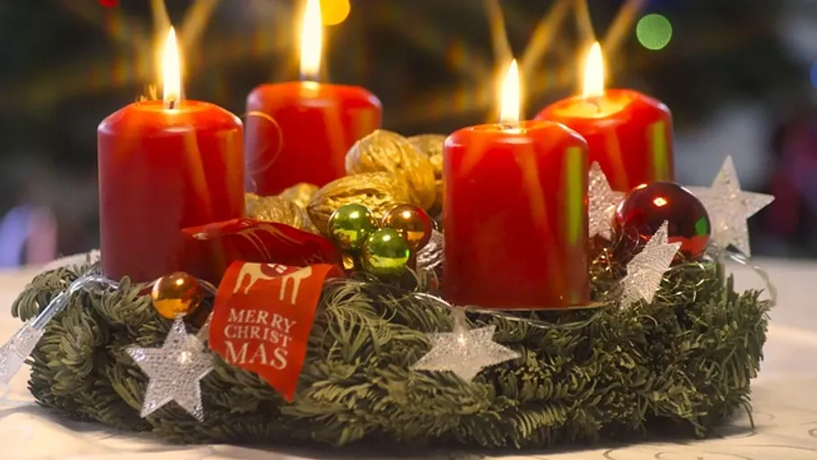 Vier brennende rote Kerzen auf Adventskranz.