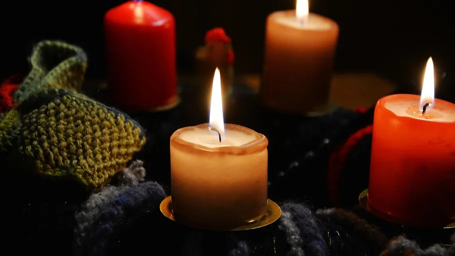 Four lit candles with knitted decorations.