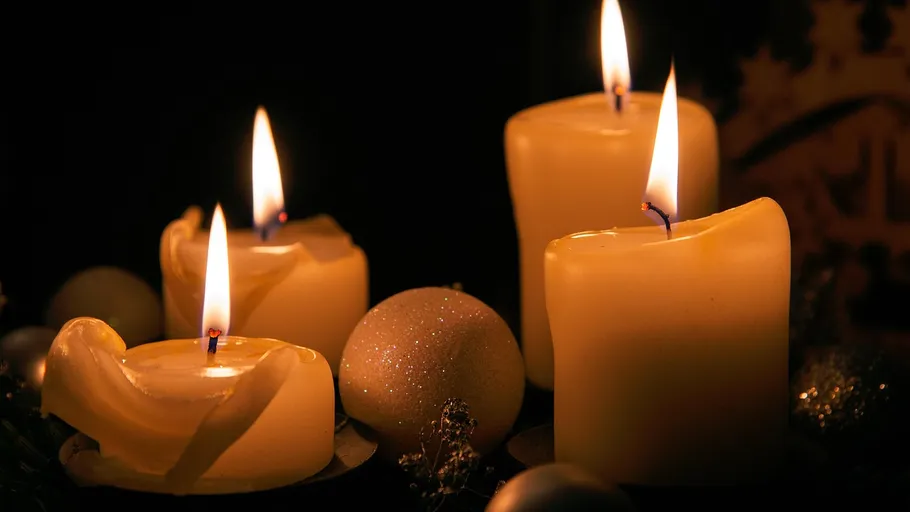 Four lit candles on dark background.