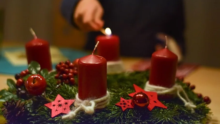 Hand zündet Kerze auf Adventskranz an.