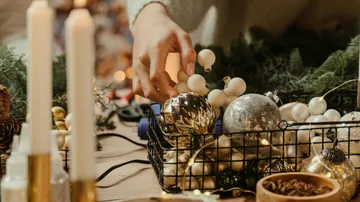 Hand places ornament in a decorative arrangement.