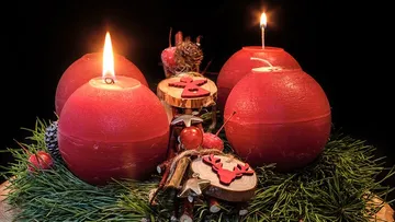 Red candles burning on festive greenery decoration.