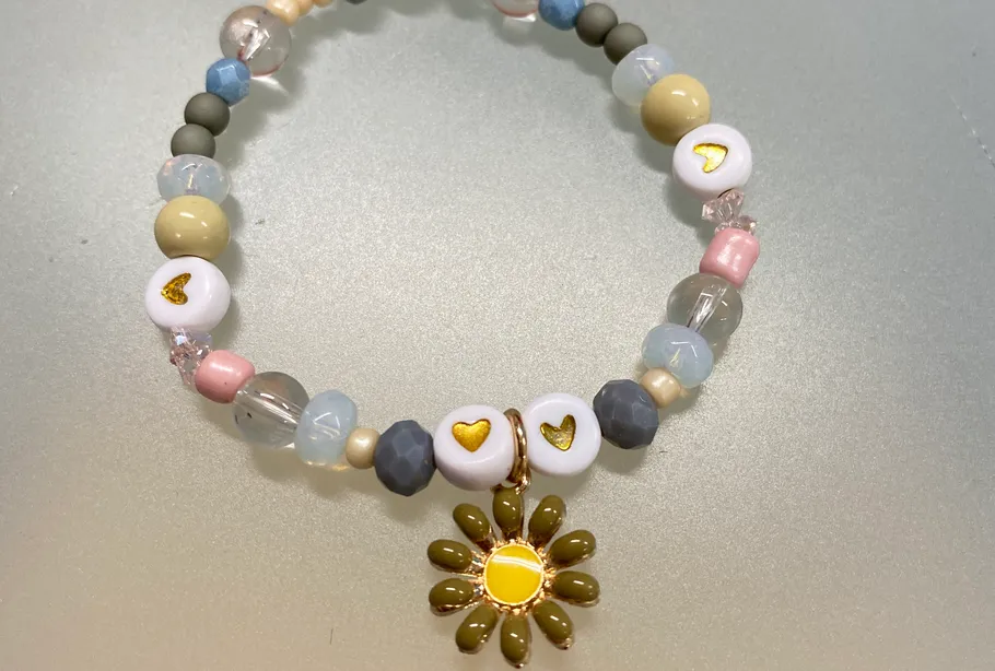 Perlenarmband mit Herzanhängern auf Tisch.