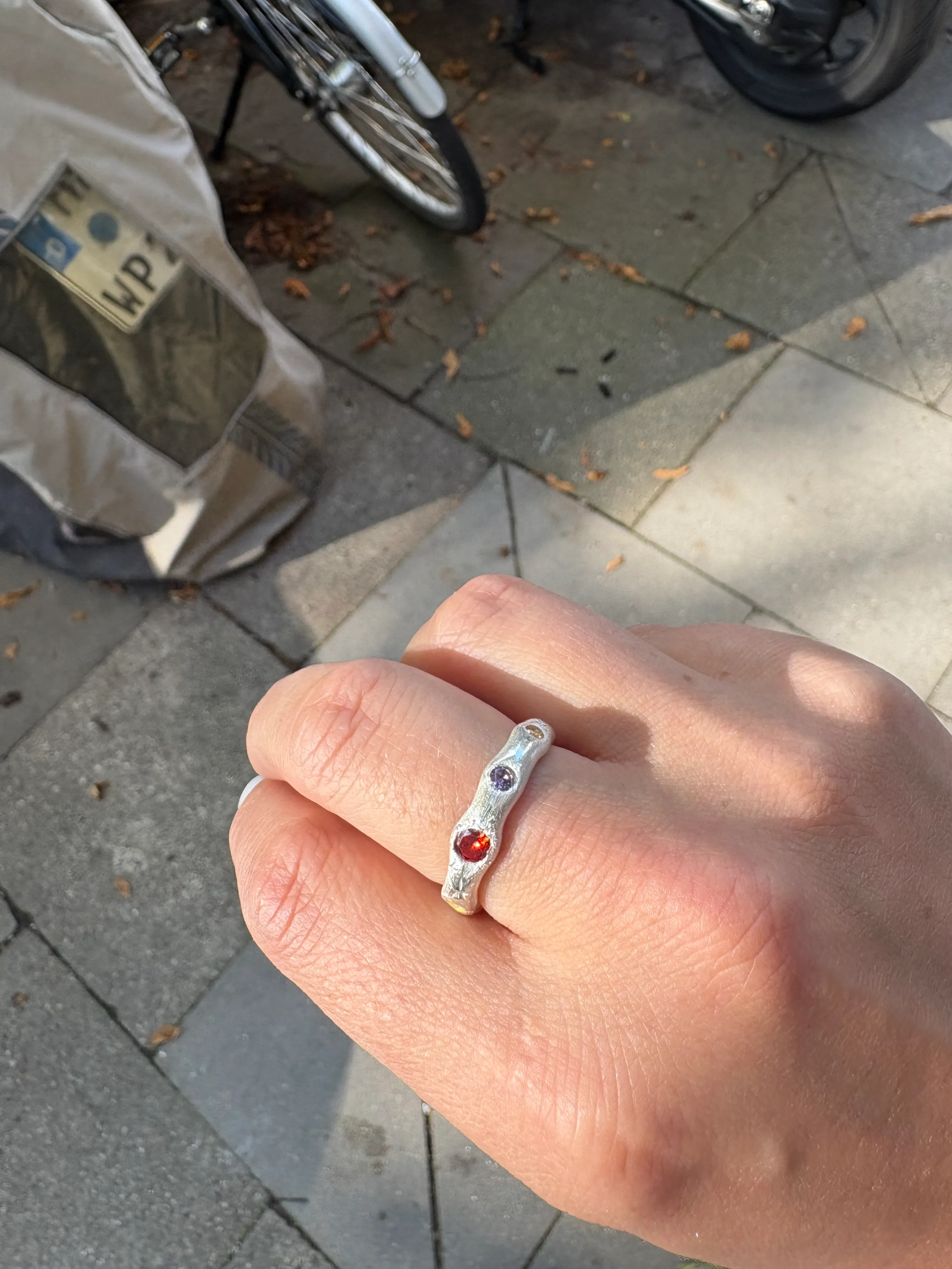 Hand trägt Silberring auf der Straße.