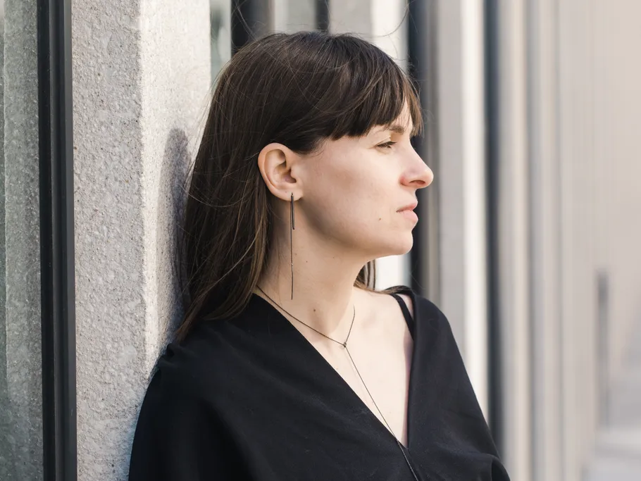 Woman in black shirt leaning on wall.