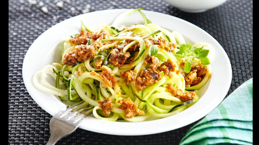 Zucchini noodles topped with sauce in a bowl.
