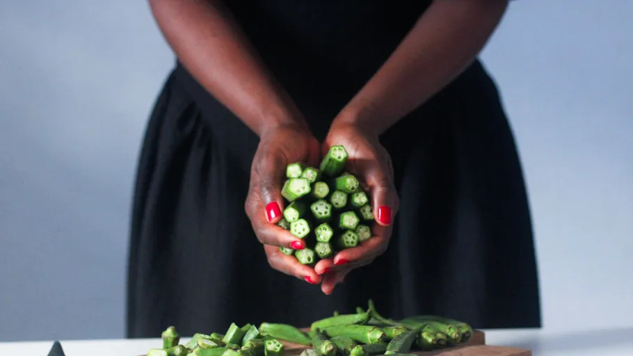 Hands holding sliced okra above cutting board.