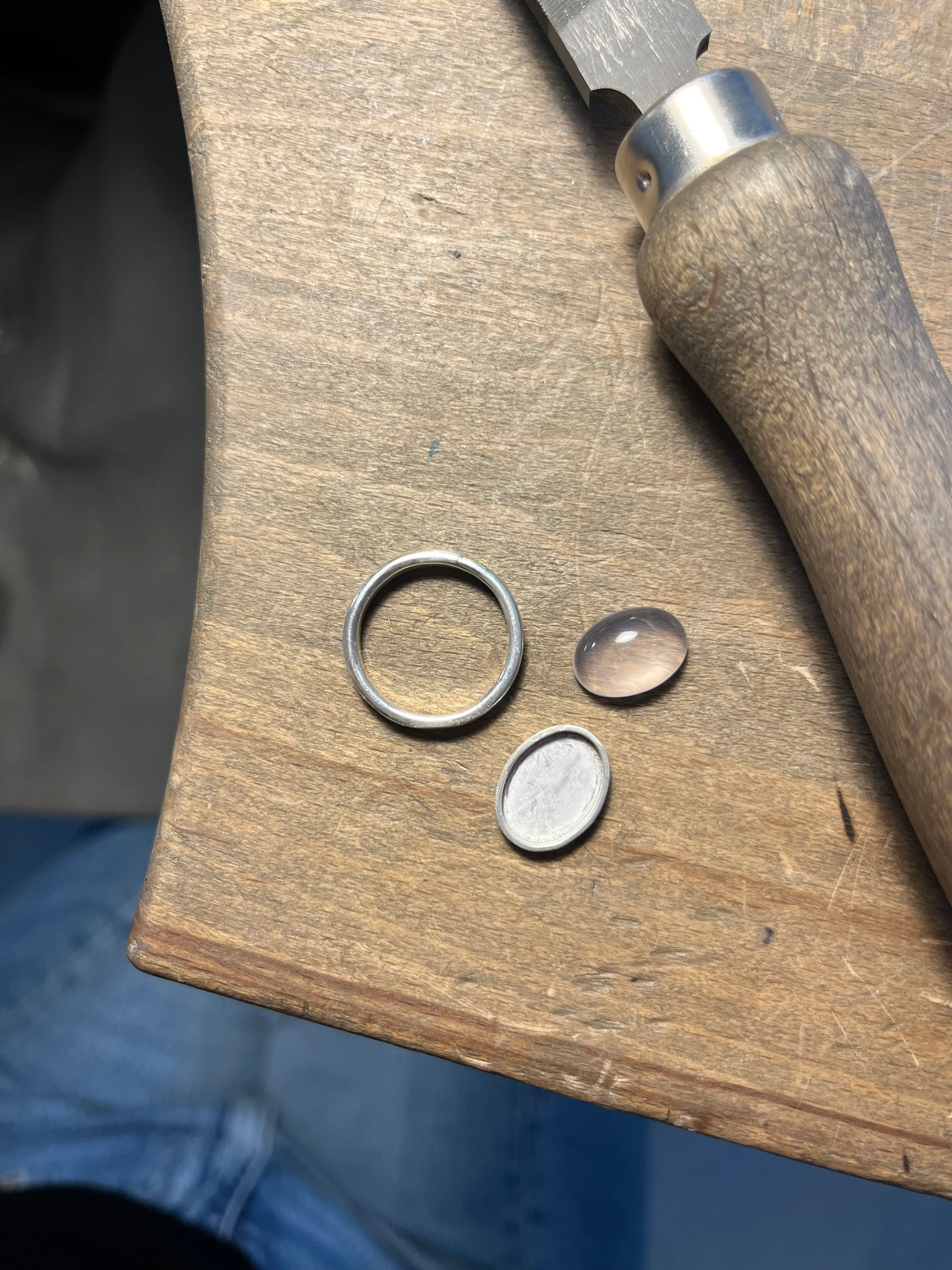 Ringteile und Werkzeug auf Holzoberfläche.