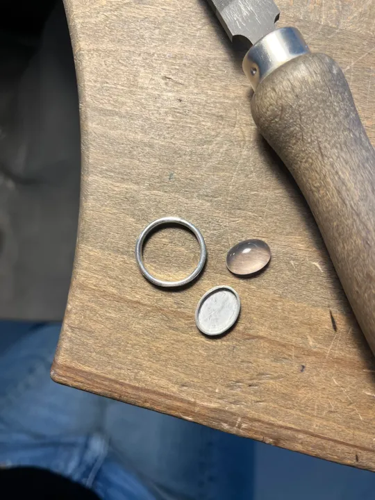 Ring parts and tool on wooden surface.
