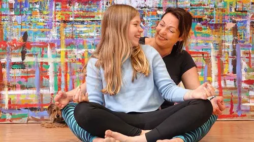 Mutter und Tochter sitzen, bunte Kunst im Hintergrund.