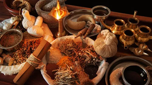 Verschiedene ayurvedische Kräuter und Werkzeuge auf einem Tisch.