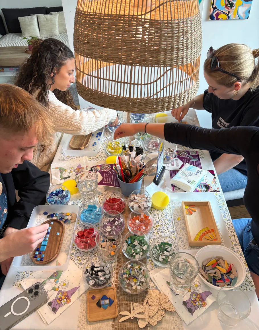 People creating mosaics at a table indoors.