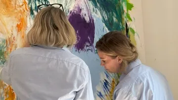 Zwei Frauen malen bunte abstrakte Kunst.