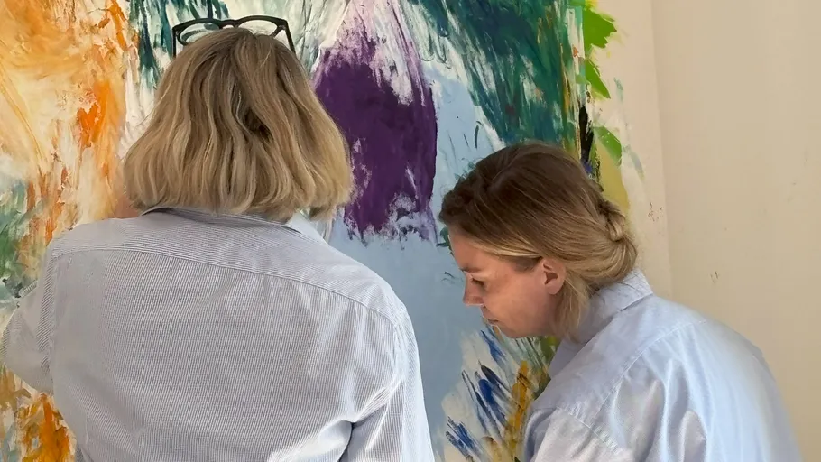 Zwei Frauen malen bunte abstrakte Kunst.