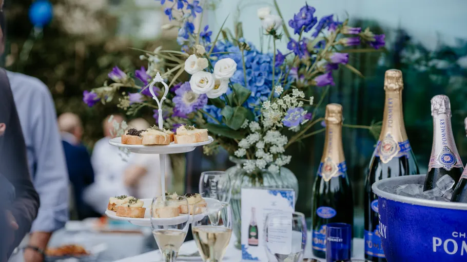 Champagnerflaschen und Canapés auf einem Tisch im Freien.