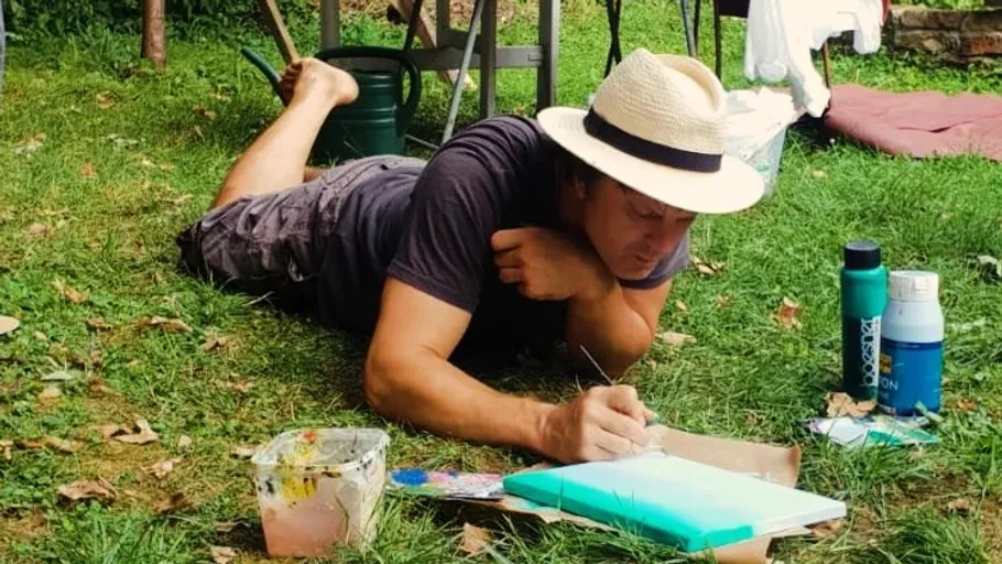 Person painting on canvas in a garden.