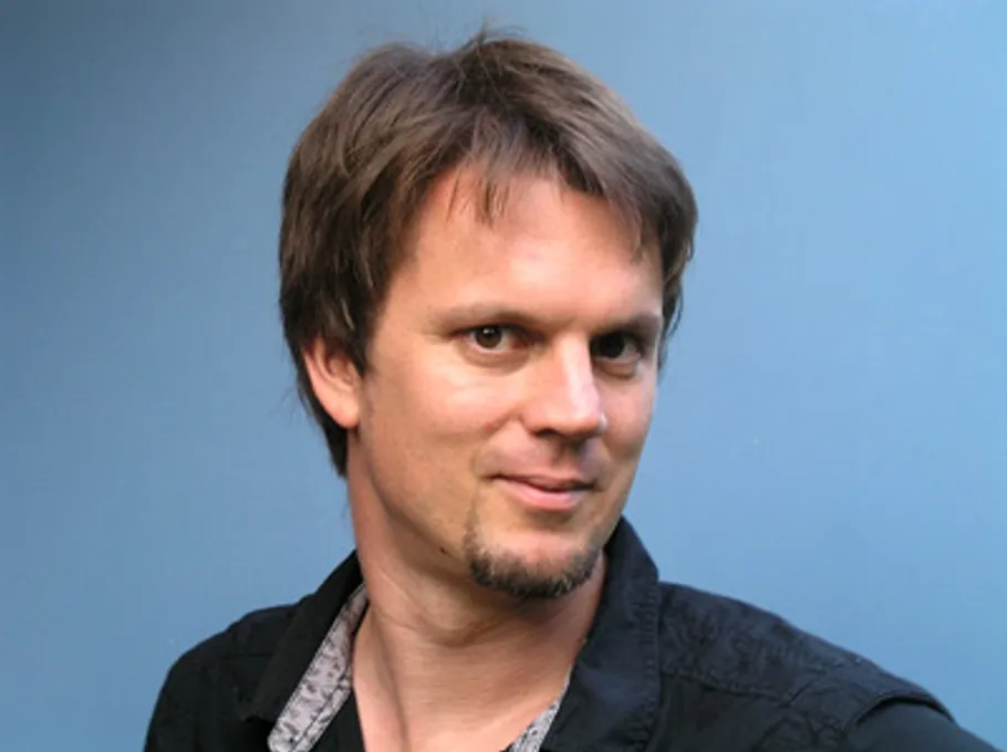 Man smiling with blue background.