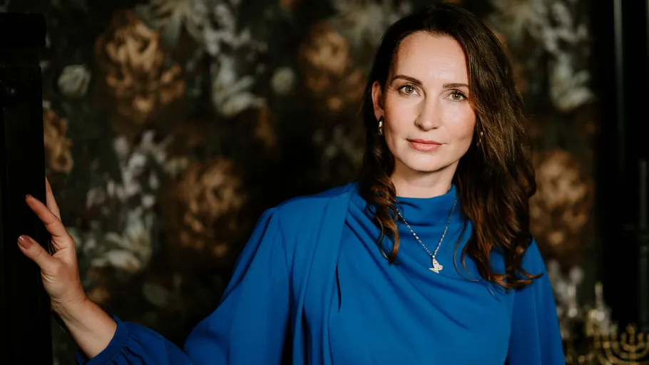 Woman in blue dress against floral wallpaper.