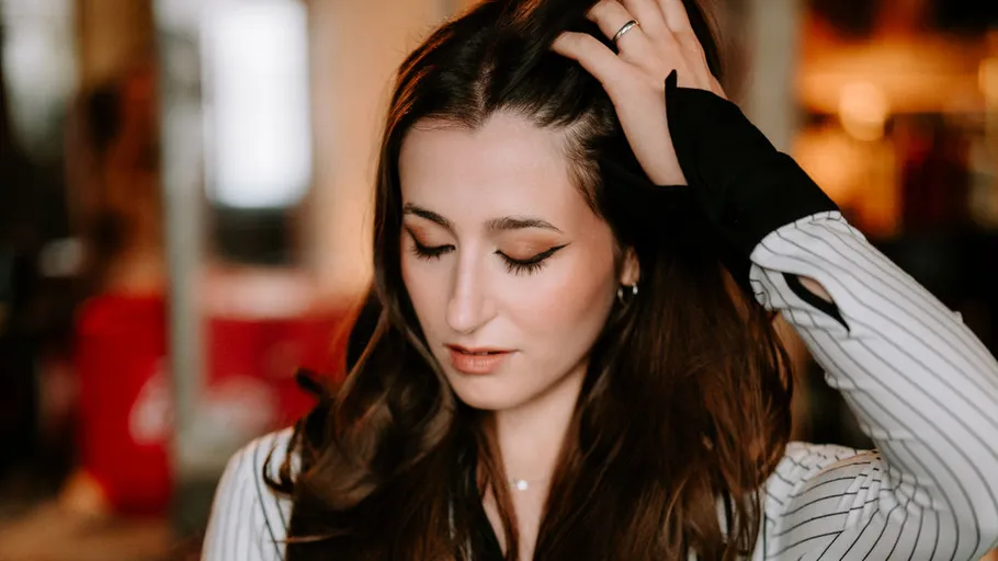 Woman touching hair, indoor environment.