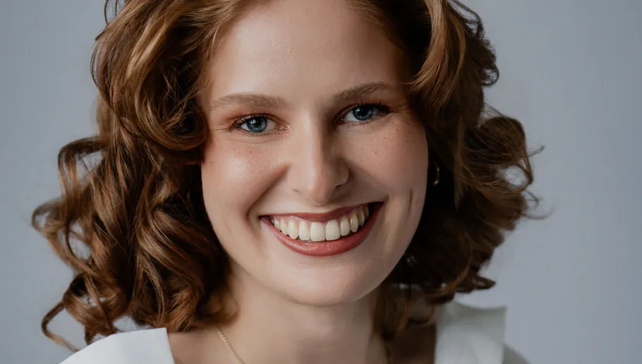 Smiling woman with curly hair, white background.