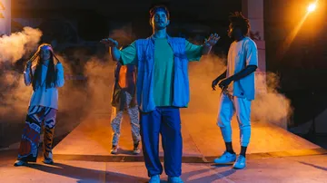 Four dancers posing under bright stage lights.