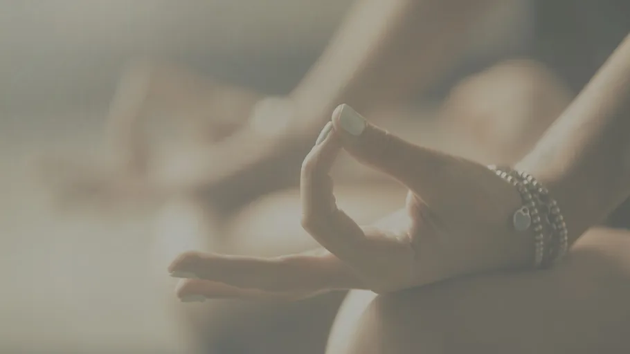 Hand in Meditationspose mit unscharfem Hintergrund.