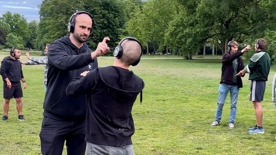 Personen mit Headsets üben Gesten in einem Park.