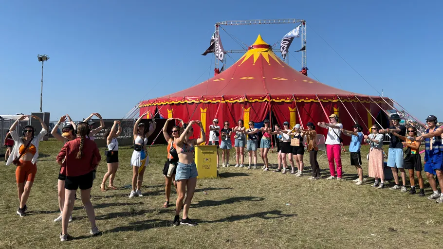 People dancing outside colorful circus tent.