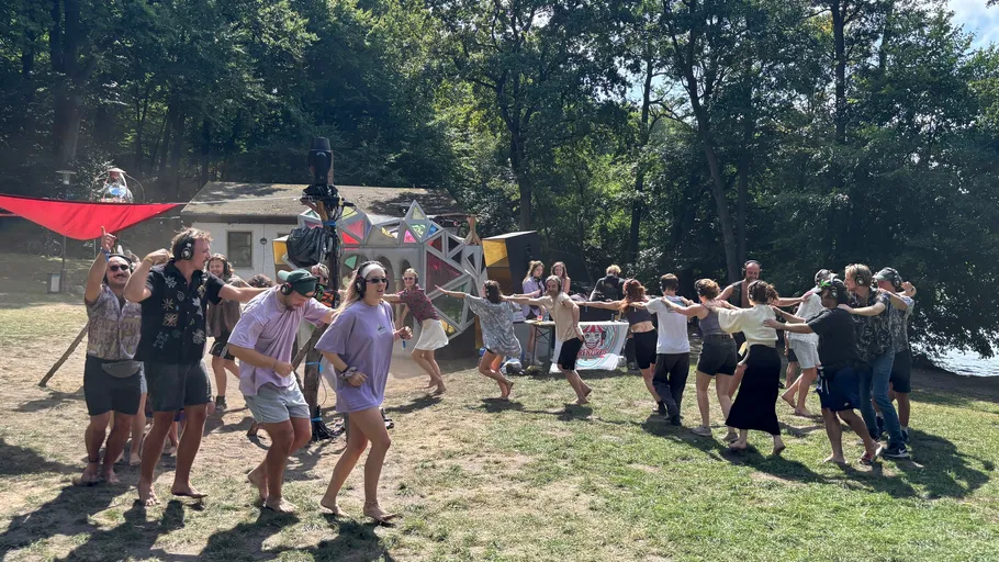 People dancing in a line outdoors, wearing headphones.