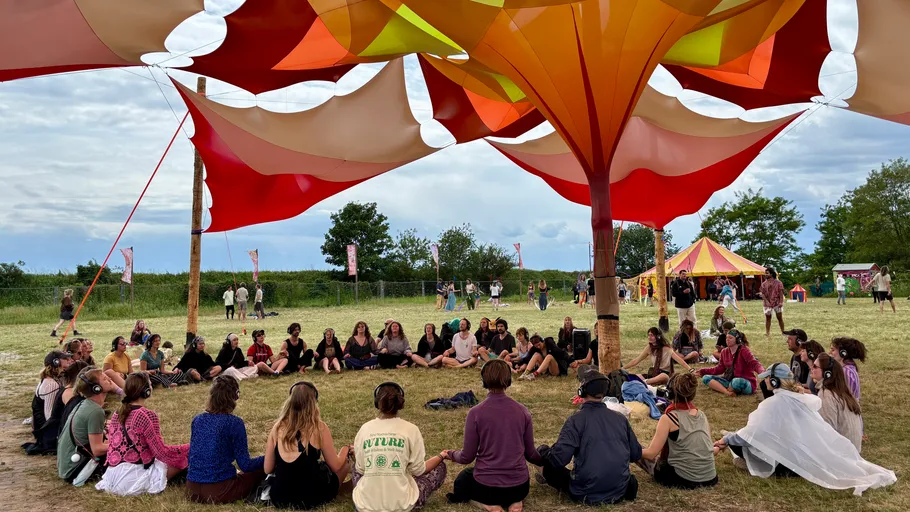 People sitting in circle under colorful canopy.