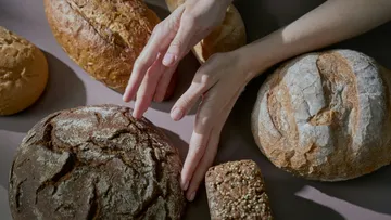 Hände berühren verschiedene Brotsorten.
