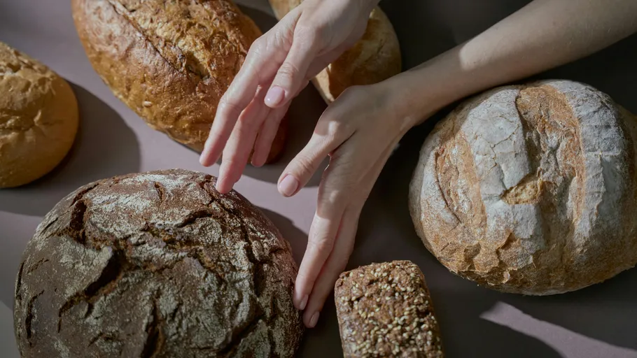 Hände berühren verschiedene Brotsorten.