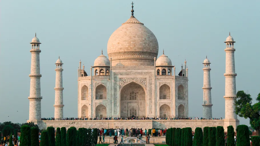 Taj Mahal mit Touristen davor, klarer Himmel.