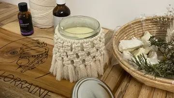 Candle in macramé holder on wooden table.