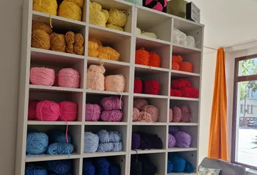 Bunte Garne auf Regal neben dem Fenster.
