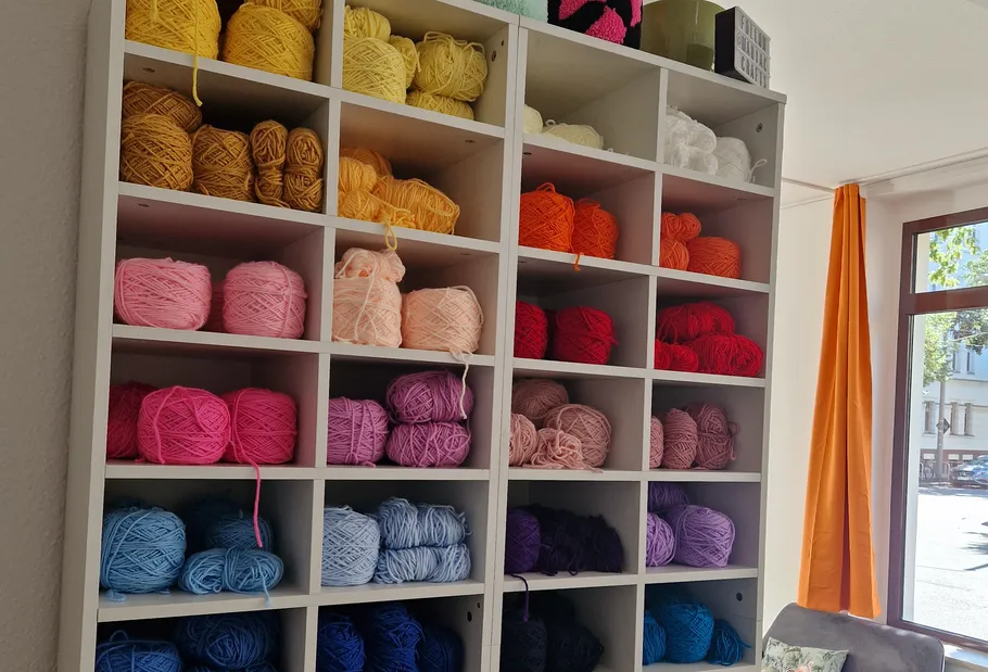 Colorful yarns organized on shelf near window.