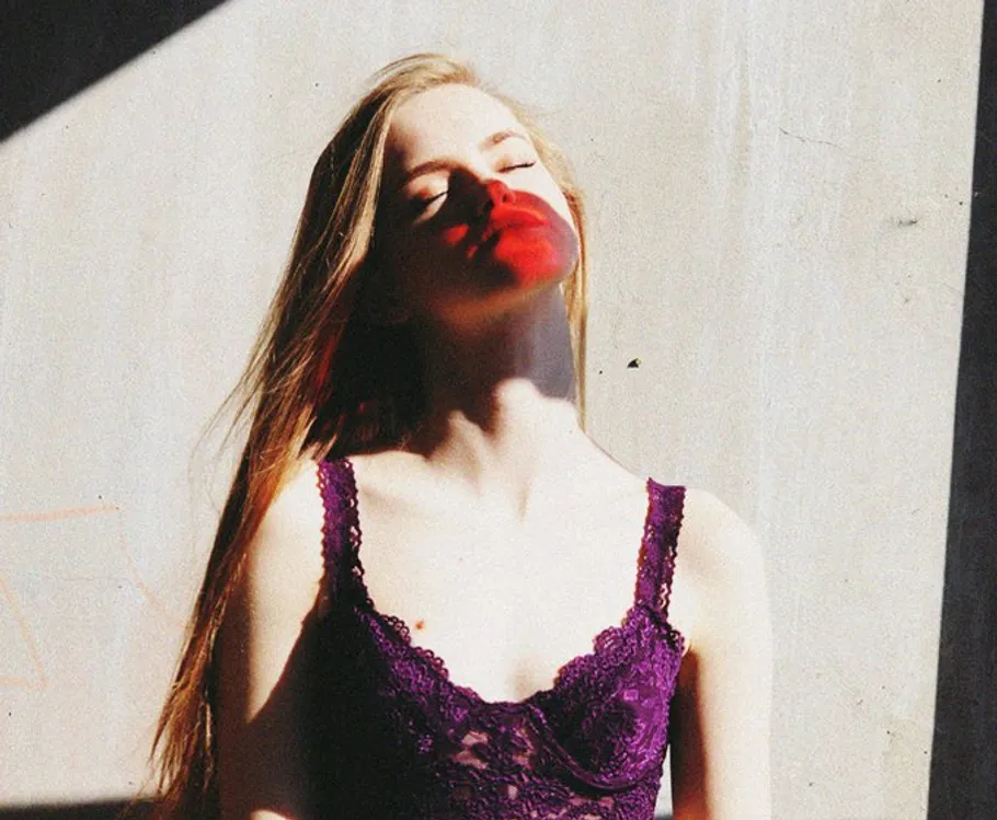 Woman in sunlight wearing purple lingerie.