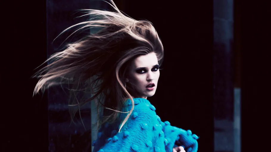Frau mit wehendem Haar in blauem Pullover.