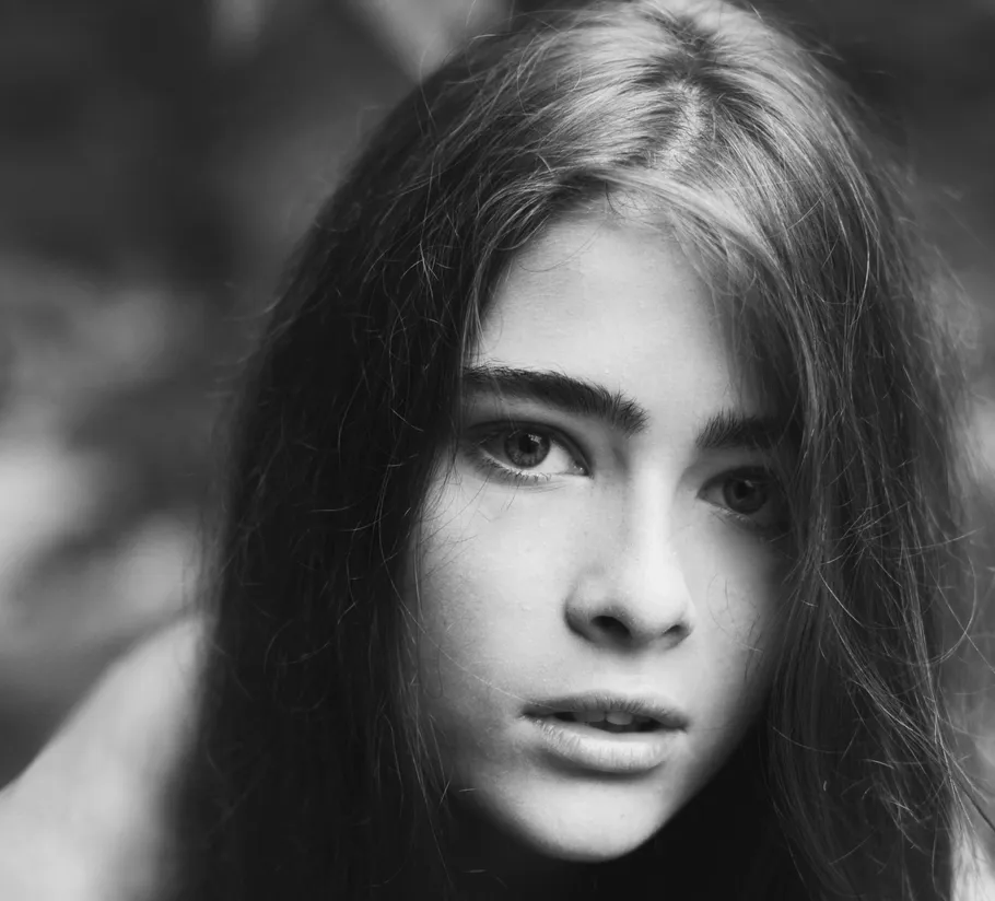 Young woman gazing intensely, outdoor setting.
