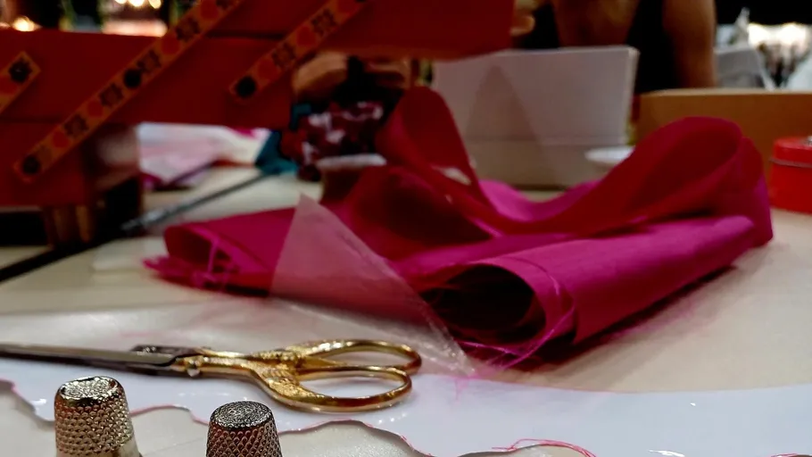 Scissors, thimbles, and fabric on a table.